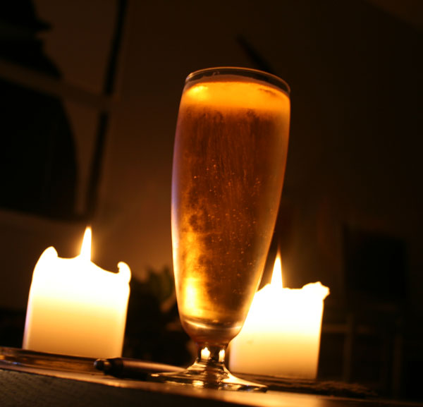 キャンドルのそばに置かれたビールグラスの写真